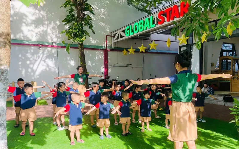 Sân trường rộng có cỏ và ánh nắng tự nhiên